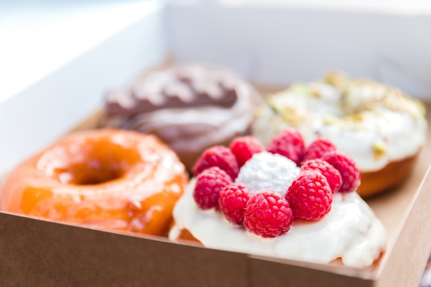 Four pieces of totally different colorful and delicious looking donuts in ecological carton box. appetising fast food dessert