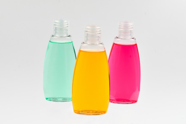 Four plastic bottles with liquid yellow, green and red soap.