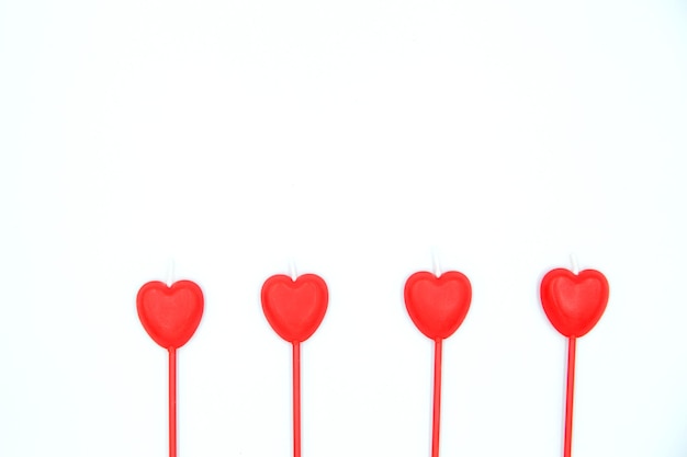 Four red heart shaped candles in a row isolated on white background