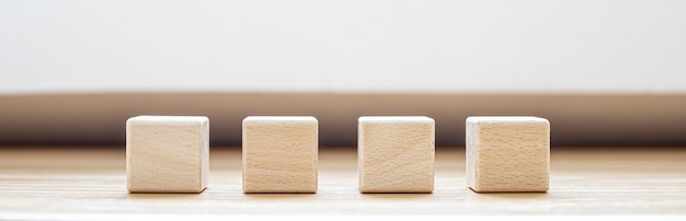 Photo four square blocks of wood are arranged on the table. a wooden block with copy space for text or symbols is used to make banners. panorama banner background with copy space.