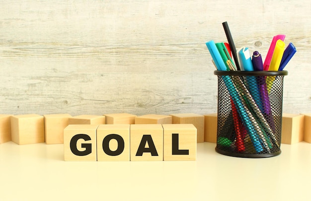 Photo four stacked wooden cubes with the letters goal on a white desktop on a gray background