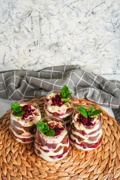 Four transparent glasses with sweet dessert with brown chocolate and white cream The cake is decorated with a mint leaf birthday portioned cake