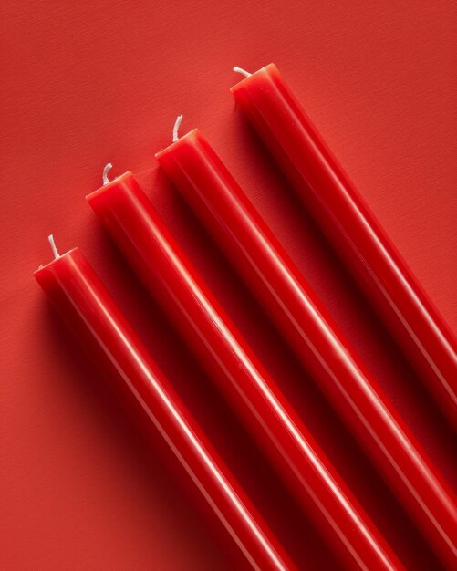 Four Vibrant Red Wax Taper Candles on Solid Red Background Elegant and Colorful Decor for