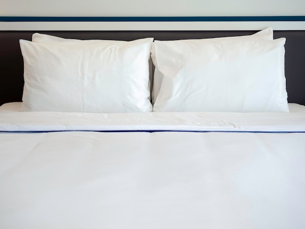 Four white clean pillows blanket and linen bed sheet in the hotel room with copy space Bedding in the bedroom front view