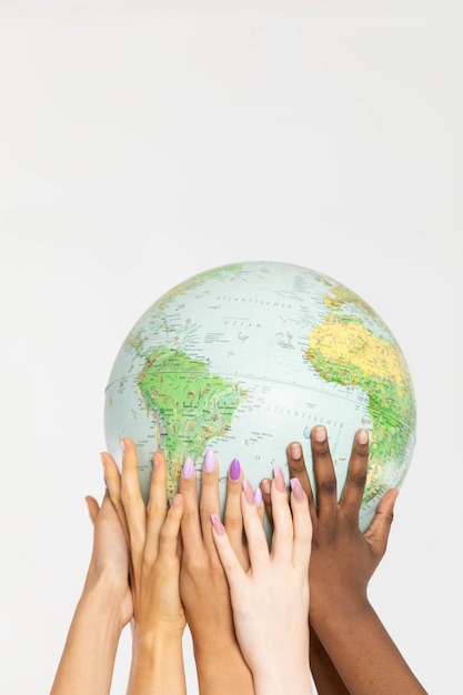 Photo four women hold the globe high above their heads and gently embrace it with their hands