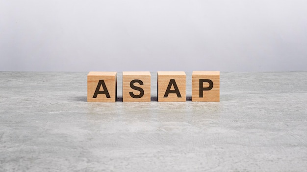 Four wooden blocks with the letters ASAP on the bright gray table business concept