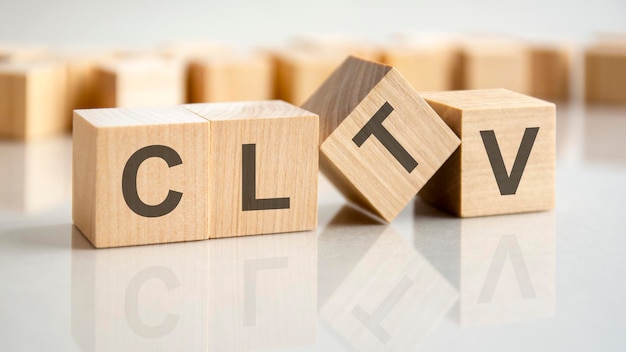 Four wooden blocks with the letters CLTV on the bright surface of a gray table the inscription on the cubes is reflected from the surface business conceptual CLTV  Customer Life Time Value