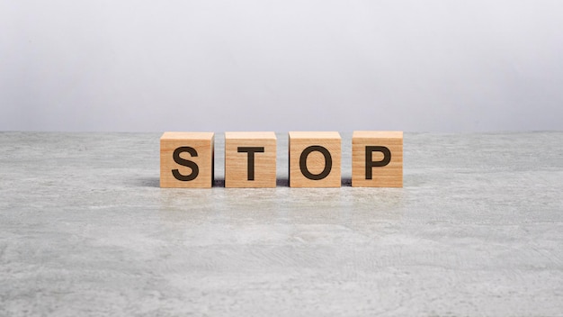 Four wooden blocks with the letters STOP on the gray table business concept