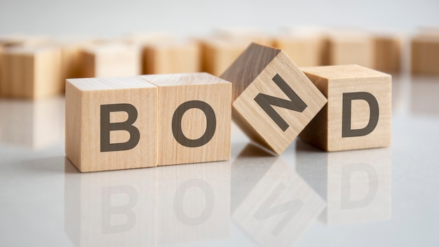 Four wooden cubes with the letters BOND on the bright surface of a gray table, business concept