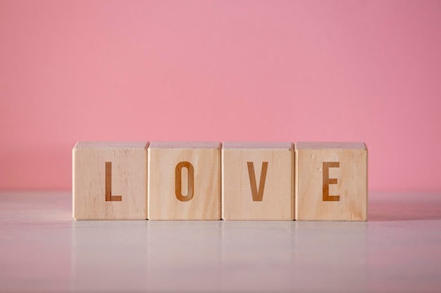 Four wooden cubes with the written word quotlovequot on pink background