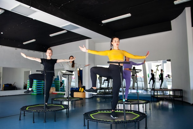 Four young women on trampoline young fitness girls trains on fitness studio