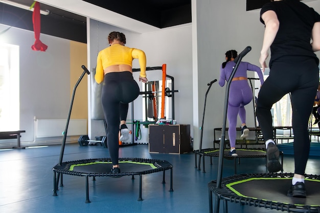 Four young women on trampoline young fitness girls trains on fitness studio