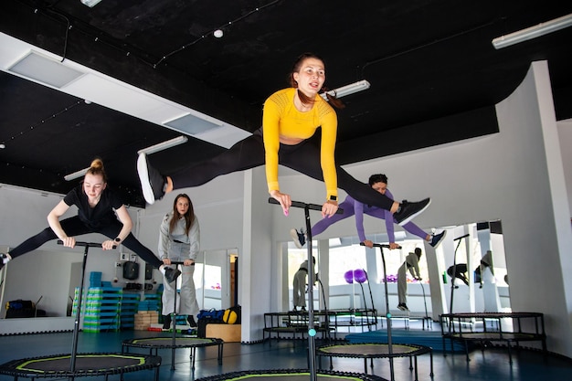 Four young women on trampoline young fitness girls trains on fitness studio