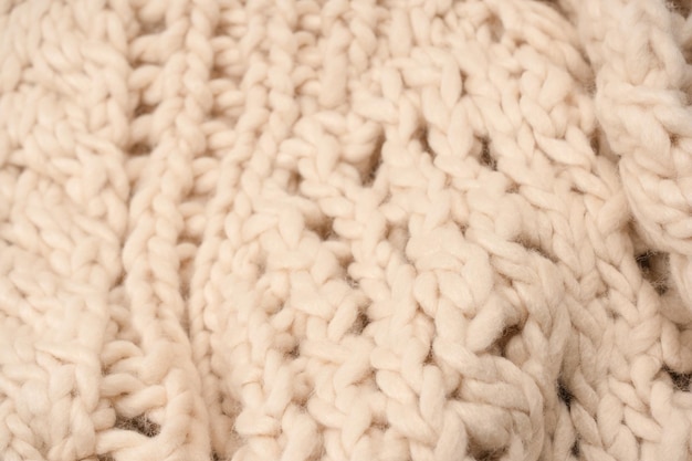 A fragment of beige knitted fabric knitted from white sheep wool