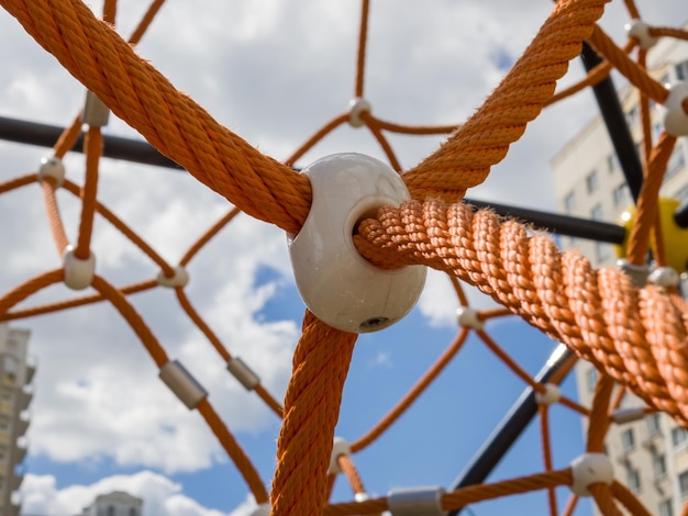 Fragment of cobweb in the playground Detail of cross orange ropes in safety climbing equipment