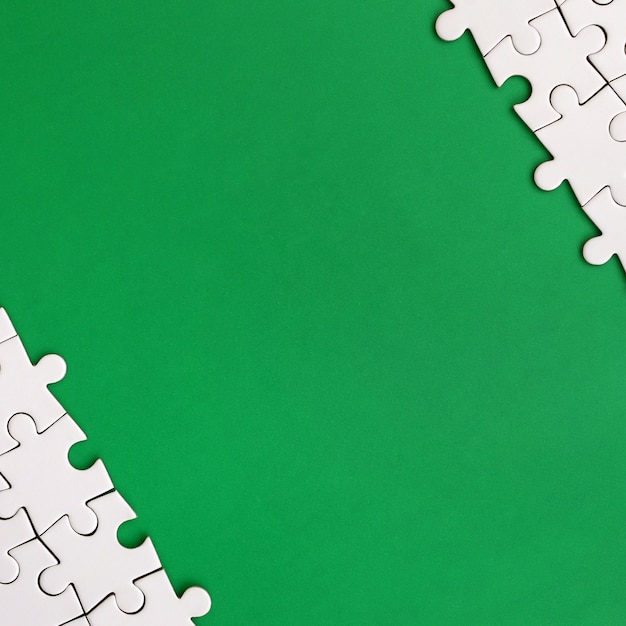 Fragment of a folded white jigsaw puzzle on the background of a green plastic surface