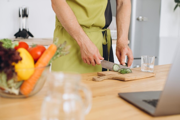 Fragment of a man making a salad from fresh vegetables in the kitchen at home