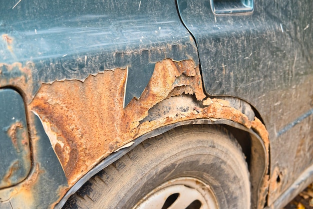 Fragment of an old damaged and rusted car