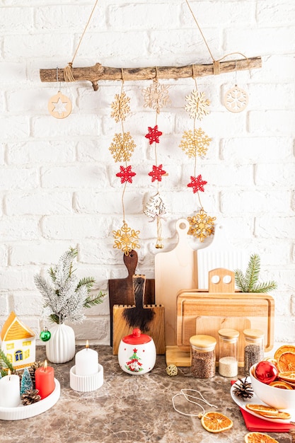 Fragment of part of a marble countertop in a modern kitchen with various kitchen utensils and a homemade Christmas ecogarland on a white brick wall