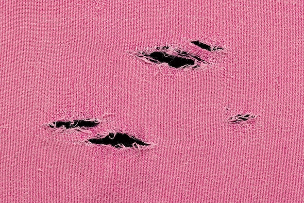 A fragment of a pink fabric with holes, as a background or texture, close-up.