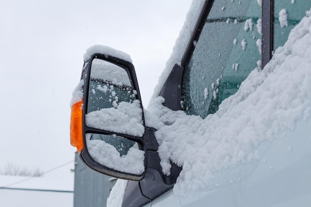 Fragment of snow covered cab of the truck on a winter cloudy sky background