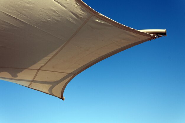 Fragment of a stretched awning against the blue sky copy space