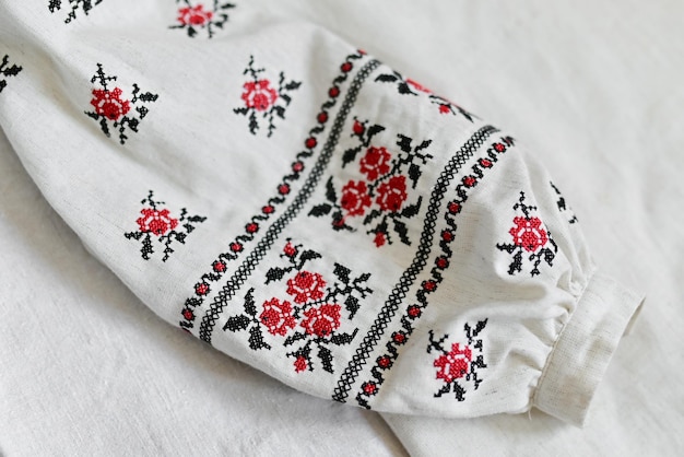 Fragment of Ukrainian national dress Vyshyvanka ethnic clothing with embroidery patterns red and black threads Closeup shot copy space