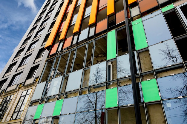 Fragment of an unfinished multi-story residential building or commercial property with concrete-metal structures and Glazing for design on an architectural theme. Reflection of trees in glass