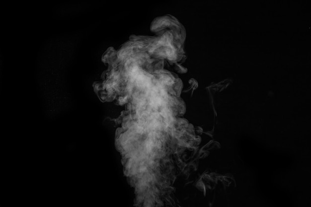 Fragment of white hot curly steam smoke isolated on a black background, close-up. Abstract background, design element