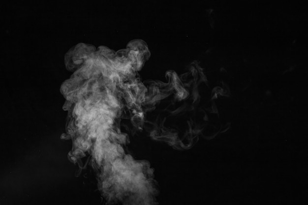 Fragment of white hot curly steam smoke isolated on a black background, close-up. Create mystical Halloween photos. Abstract background, design element