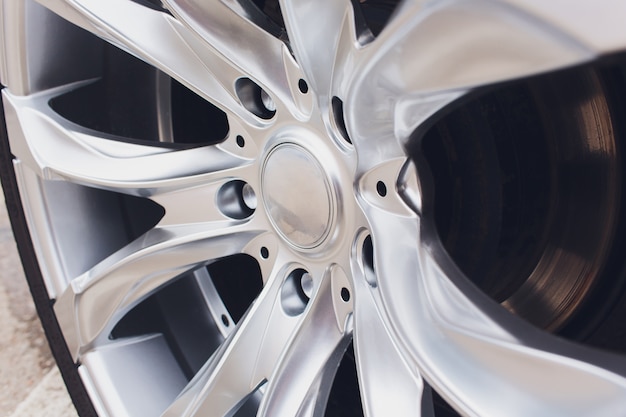 Fragment of white modern car with wheel on steel disc, closeup photo.