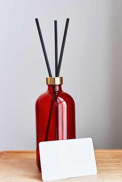 Fragrance diffuser bottle and blank white paper card on a wooden tray