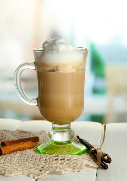 Fragrant coffee latte in glass cup with spices on wooden table