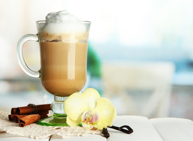 Fragrant coffee latte in glass cup with spices, on wooden table