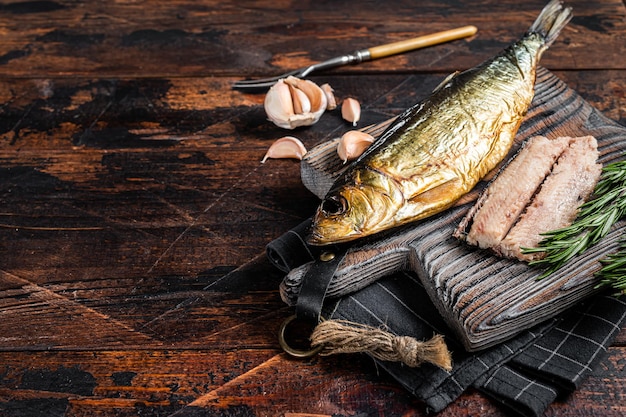 Fragrant Smoked herring fish fillet on wooden board with herbs. Wooden background. Top view. Copy space.