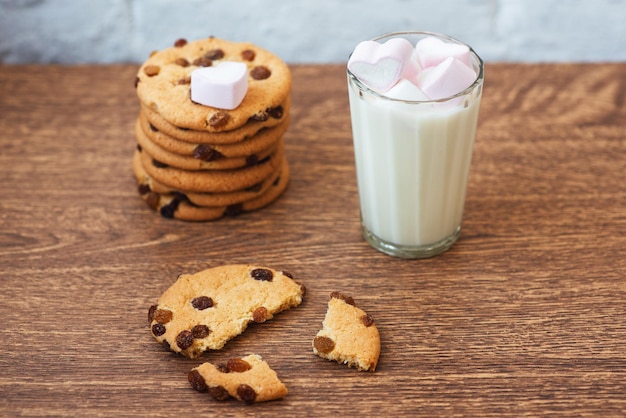 Fragrant tasty homemade cookies with raisins marshmallow in a heart form and a glass of fresh milk on the table