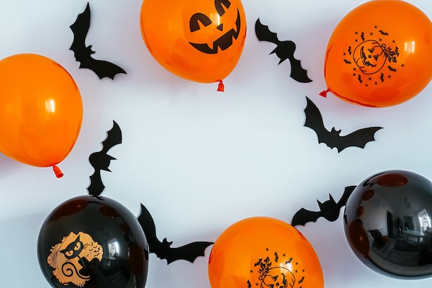 Frame of black and orange halloween baloons with pumpkin and cat faces and flying bats