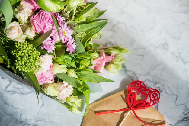 Frame composition with bouquet with roses eustoma envelope and red heart Floral decorative elements on marble backgroundHappy Women's Day happy mothers day valentines day concept