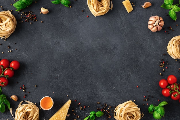 Frame of fettuccine with ingredients for cooking Italian pasta on dark