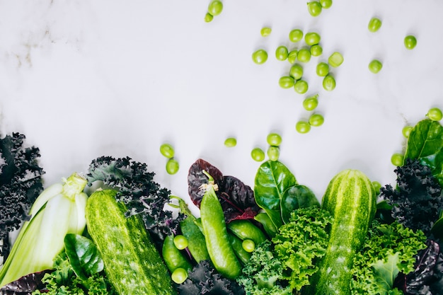 Frame of fresh green vegetables on a marble background, copy space, flay lay, top view