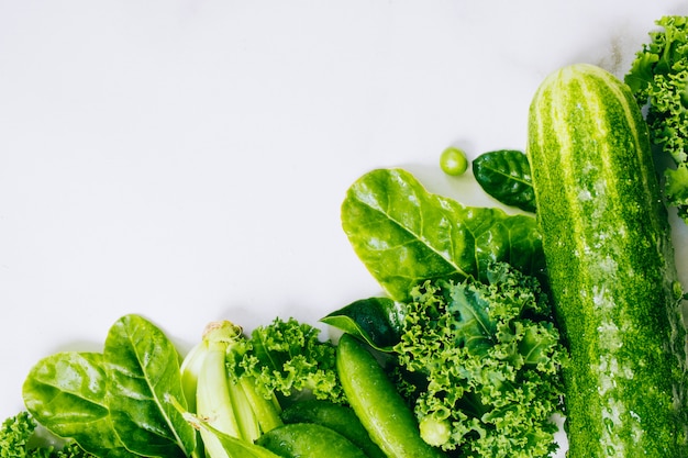 Frame of fresh green vegetables on a marble background, copy space, flay lay, top view