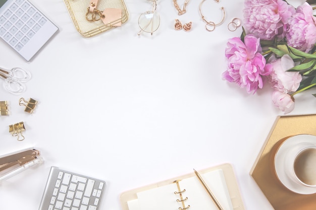 Frame of gold stationery on a white background. Diary, calculator, coffee mug, stapler, hole punch, pen, glasses and keyboard.