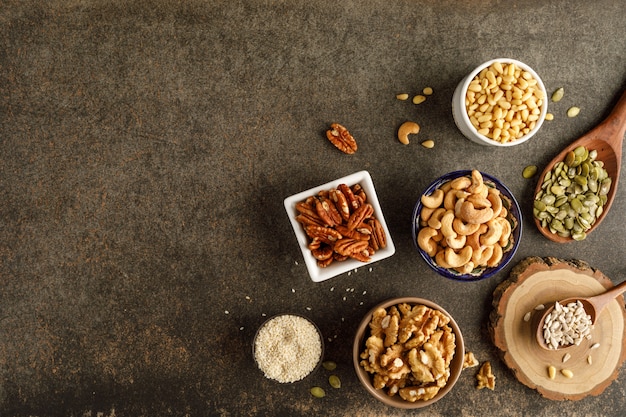 Frame made of different types of nuts in bowls. Top view. Copy space