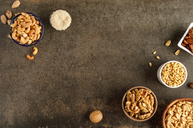 Frame made of different types of nuts in bowls. Top view. Copy space