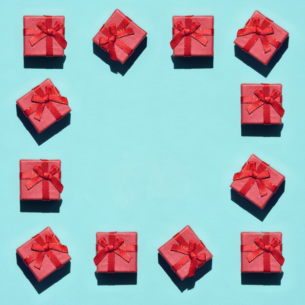 Frame of many small red pink gift boxes on green