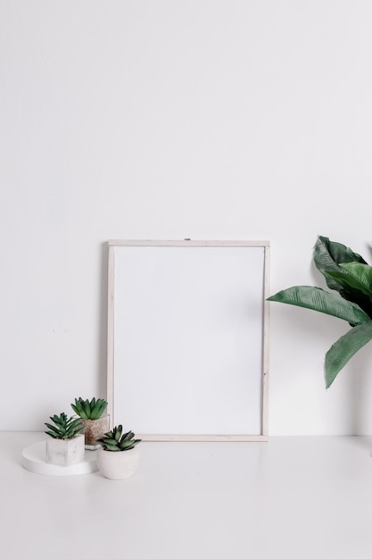 Frame mockup with artificial green and succulent flower on pots in warm neutral minimalist interior