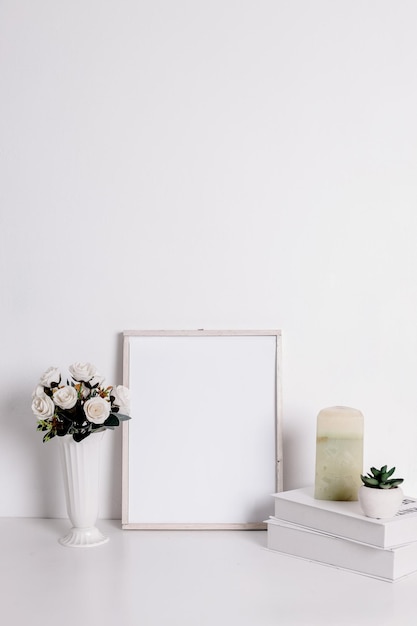 Frame mockup with artificial rose flower on vase books candle and succulent flower on pot