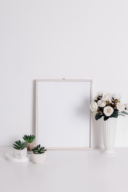 Frame mockup with artificial rose flower on vase and succulents flower on pots