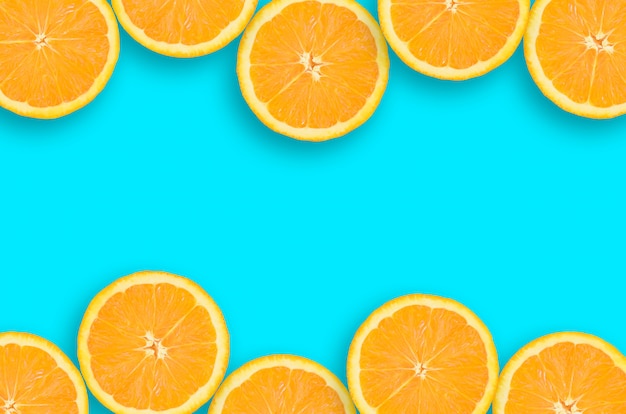 Frame of an orange citrus slices on bright blue background