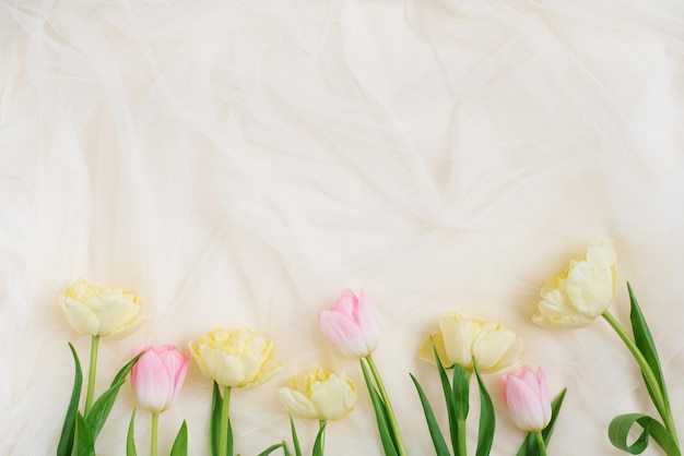 Frame of spring tulip flowers on a beige background with a copy space Flat lay for wedding day Easter and Valentine's Day